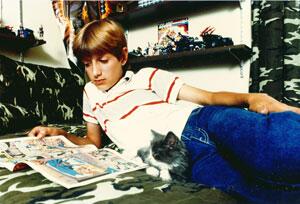 Ryan White reading a comic book with his cat on his bedroom floor.